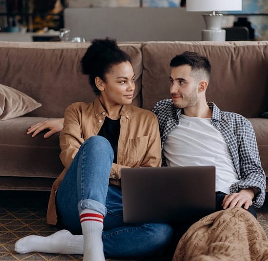 pexels-photo-6894032 Couple sitting on floor with laptop, sharing a warm and cozy moment.