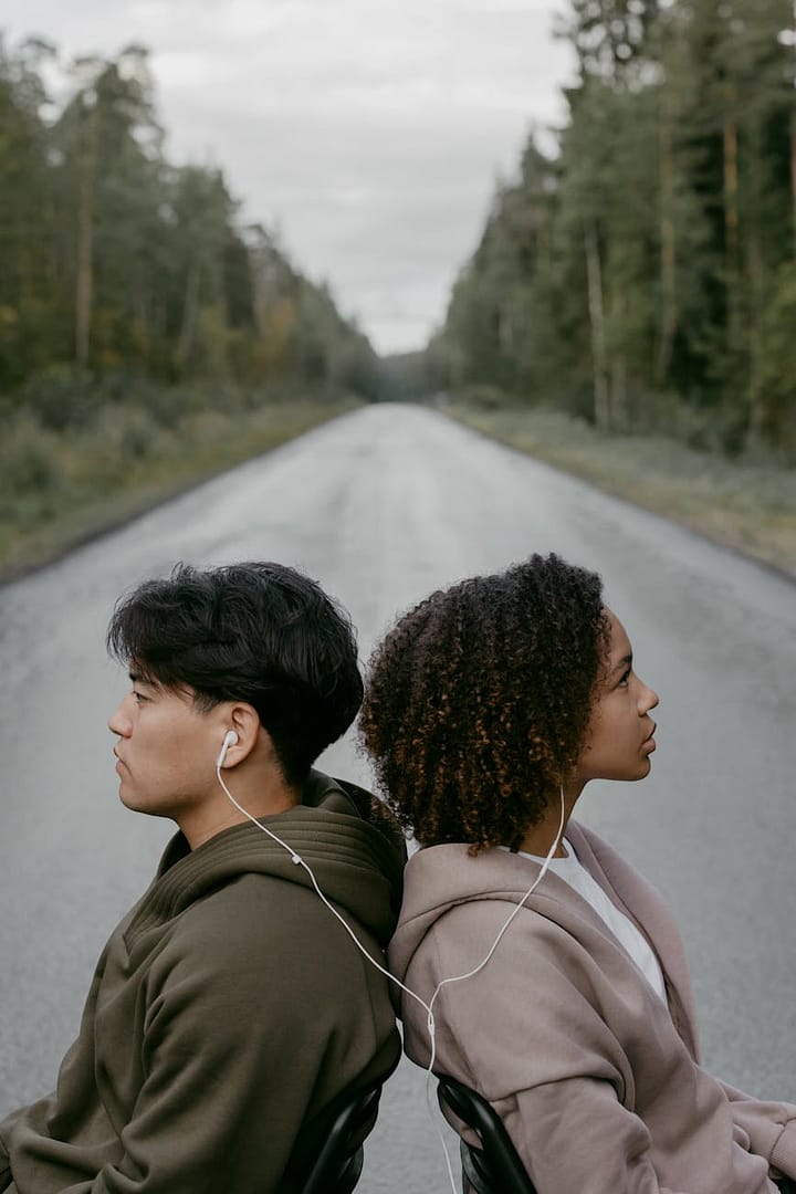 a man and woman sitting back to back while listening to music